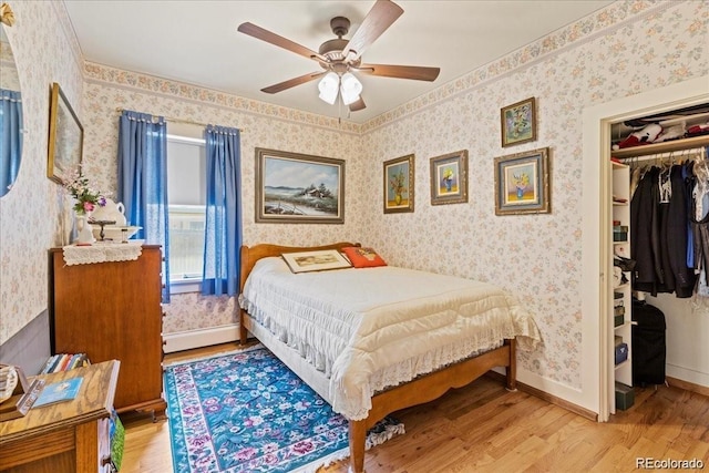 7750 W 5th Ave, Lakewood, CO 80226 - bedroom featuring wood finished floors, a closet, wallpapered walls, a ceiling fan, and a walk in closet