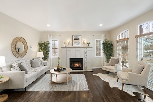 living room with a fireplace, dark wood-type flooring, and a healthy amount of sunlight