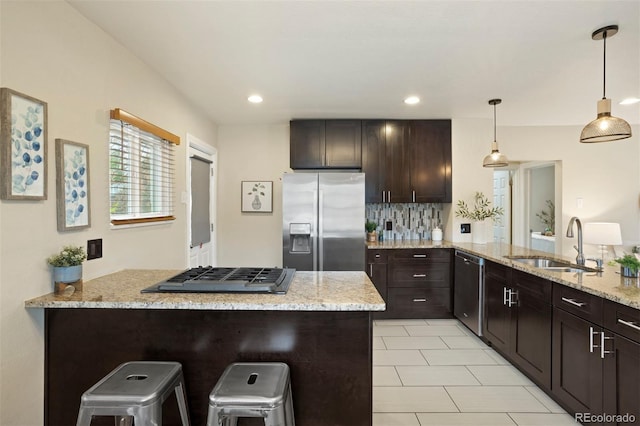 kitchen with kitchen peninsula, appliances with stainless steel finishes, a kitchen breakfast bar, and sink