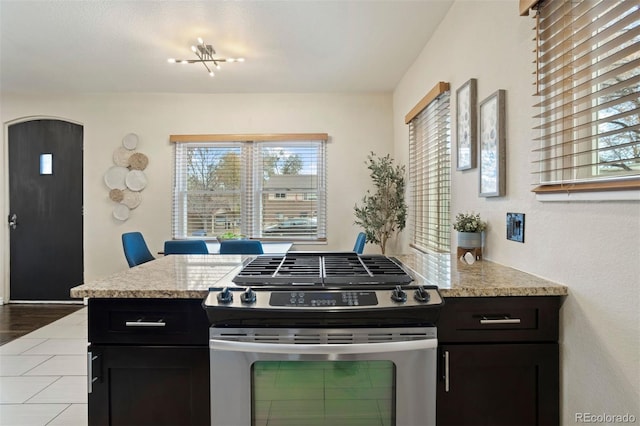 kitchen featuring a wealth of natural light, light stone counters, hardwood / wood-style flooring, and stainless steel range with gas stovetop