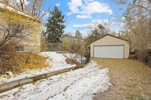 yard layered in snow featuring a garage and an outdoor structure