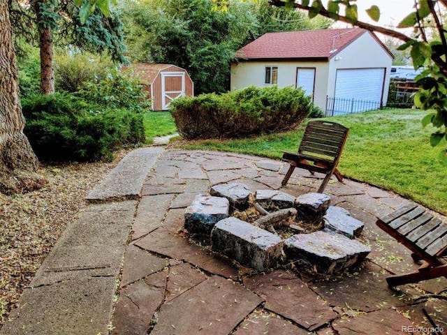 view of patio featuring a garage, an outdoor fire pit, and a storage shed