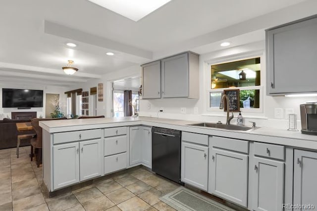 kitchen featuring black dishwasher, a sink, light countertops, a peninsula, and gray cabinetry