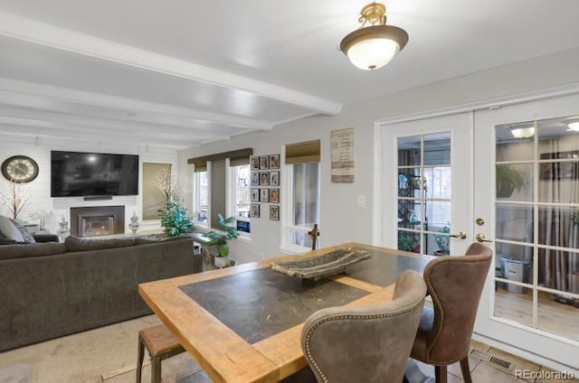 dining area with french doors, beamed ceiling, visible vents, and a glass covered fireplace