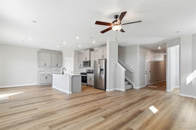 kitchen featuring a sink, open floor plan, light wood-type flooring, and stainless steel appliances