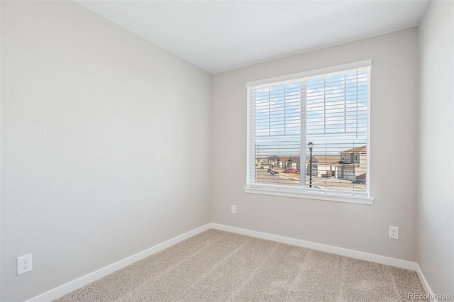 carpeted spare room featuring baseboards