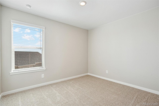 carpeted empty room featuring baseboards