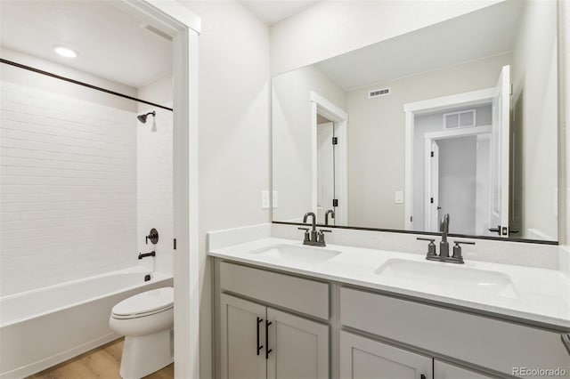 full bathroom with visible vents, a sink, toilet, and wood finished floors