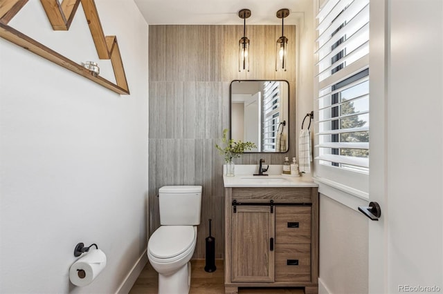 bathroom featuring toilet, baseboards, wood finished floors, and vanity