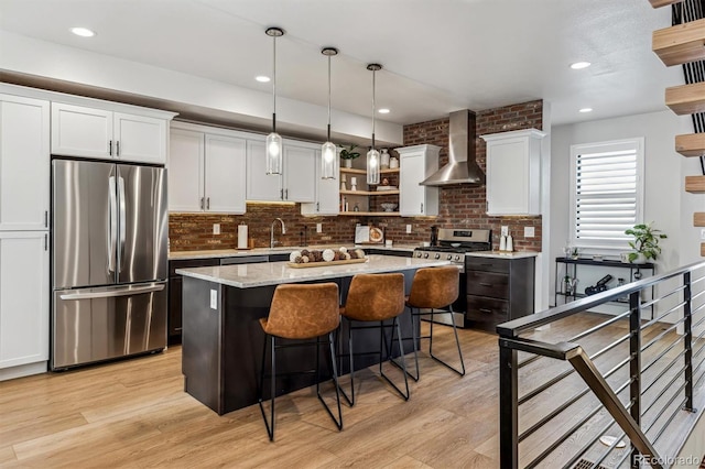 kitchen with white cabinets, wall chimney exhaust hood, pendant lighting, stainless steel appliances, and open shelves