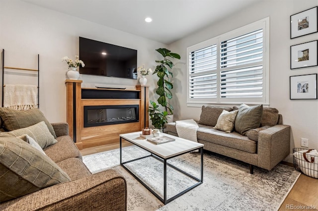 living area featuring wood finished floors, a glass covered fireplace, and recessed lighting