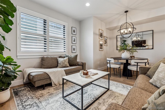 living area featuring recessed lighting, baseboards, a notable chandelier, and light wood finished floors