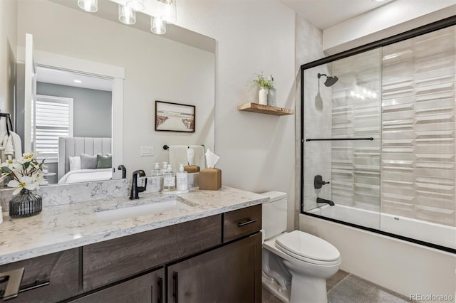 ensuite bathroom with connected bathroom, vanity, toilet, and bath / shower combo with glass door