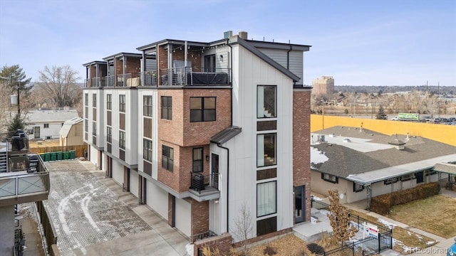 5423 S Prince St Unit B, Littleton, CO 80120 - back of property with a balcony, brick siding, concrete driveway, and a garage