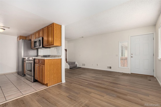 kitchen featuring stainless steel appliances, light hardwood / wood-style flooring, and a textured ceiling