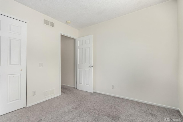 unfurnished bedroom featuring light carpet and a textured ceiling