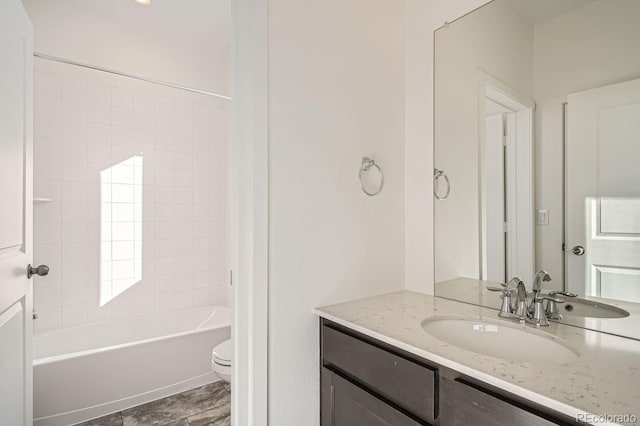 full bathroom with tiled shower / bath, vanity, and toilet