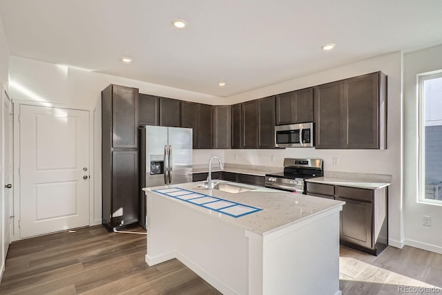 kitchen with stainless steel appliances, a kitchen island with sink, sink, and hardwood / wood-style floors