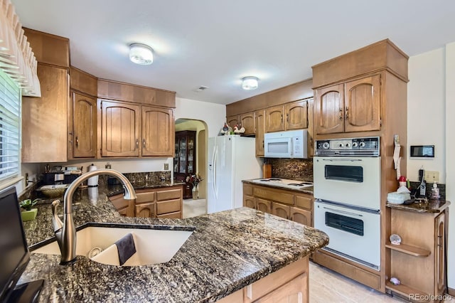 3724 S Poplar St, Denver, CO 80237 - kitchen featuring white appliances, arched walkways, a peninsula, tasteful backsplash, and dark stone counters