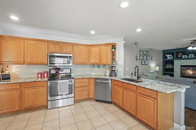 kitchen with appliances with stainless steel finishes, a sink, a peninsula, open floor plan, and open shelves