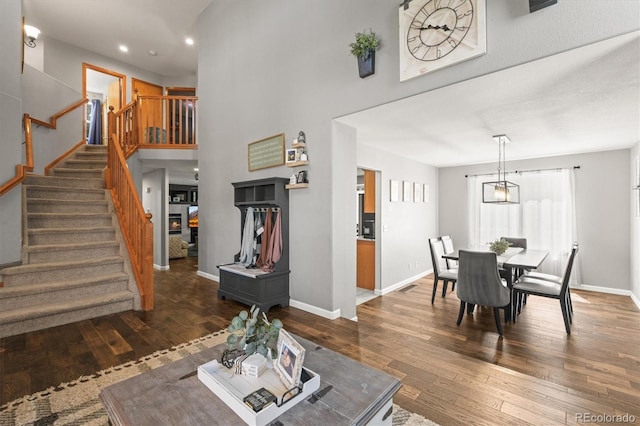 dining area featuring stairway, wood-type flooring, baseboards, recessed lighting, and a high ceiling
