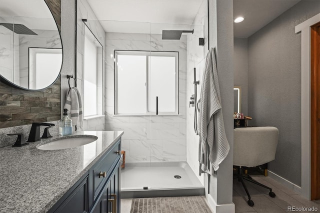 bathroom with a marble finish shower, vanity, and baseboards