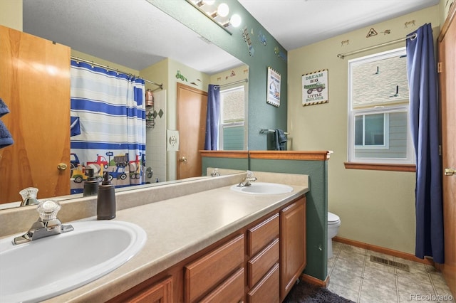 bathroom with toilet, double vanity, a shower with curtain, and baseboards