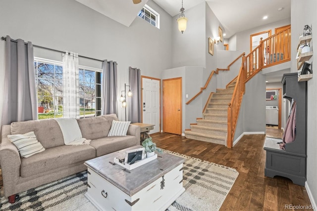 living room with a towering ceiling, dark wood finished floors, stairs, and baseboards