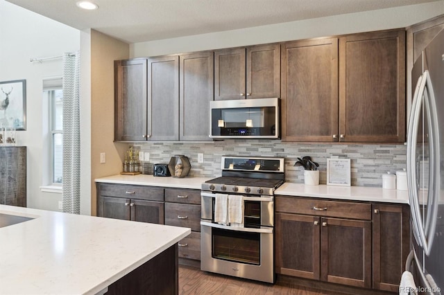 kitchen featuring dark brown cabinets, stainless steel appliances, tasteful backsplash, and dark hardwood / wood-style floors