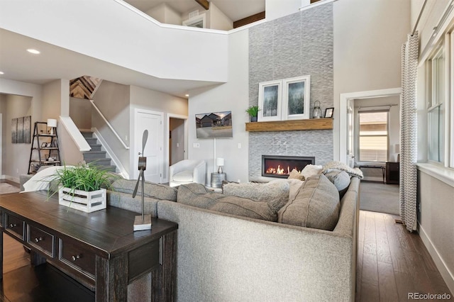 living room with a large fireplace, wood-type flooring, and a high ceiling