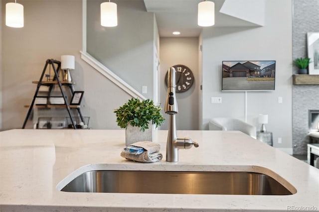 kitchen with light stone countertops, hanging light fixtures, and sink