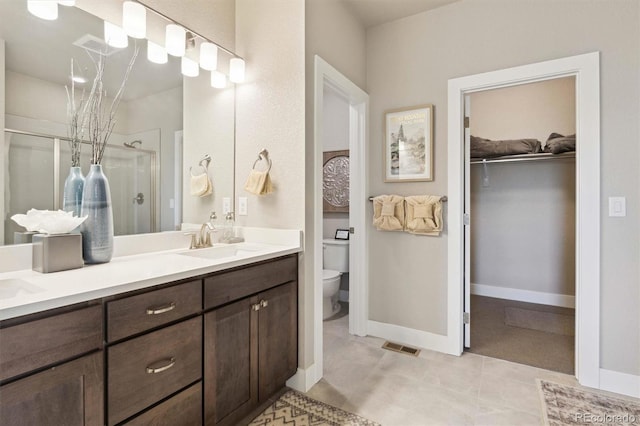 bathroom with tile patterned floors, vanity, toilet, and a shower with shower door