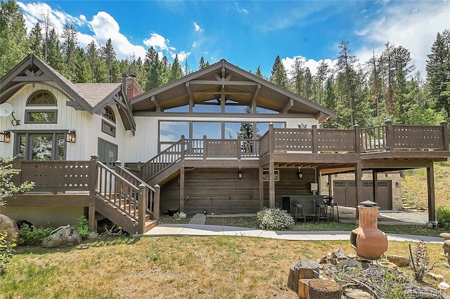 rear view of house featuring a wooden deck and a yard