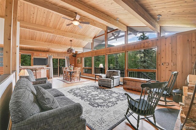 living room featuring wooden walls, wood ceiling, ceiling fan, light hardwood / wood-style floors, and lofted ceiling with beams