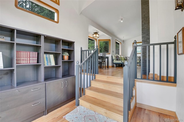 stairs with vaulted ceiling and light wood-type flooring