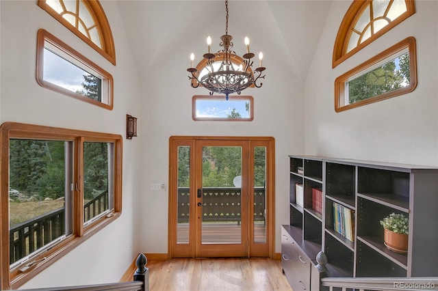 foyer entrance featuring an inviting chandelier, a wealth of natural light, light hardwood / wood-style flooring, and high vaulted ceiling