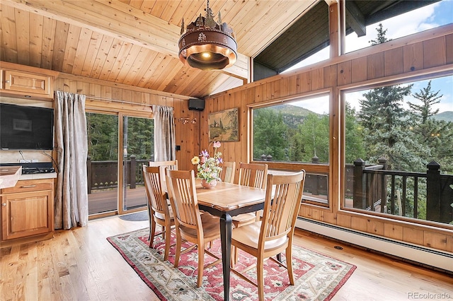 dining space featuring a baseboard radiator, wooden walls, lofted ceiling with beams, and light hardwood / wood-style flooring