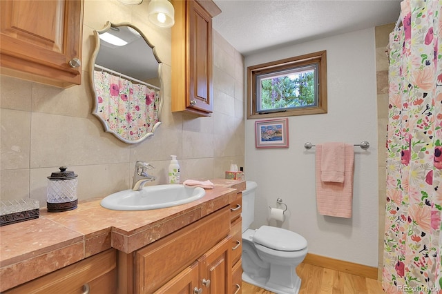 bathroom with toilet, wood-type flooring, a textured ceiling, vanity, and backsplash