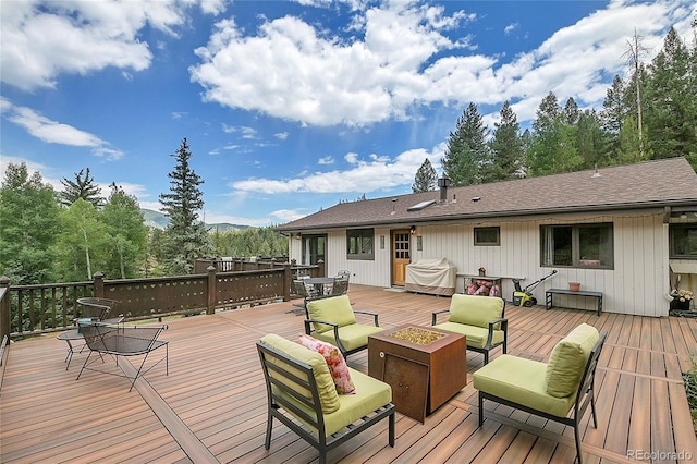 wooden deck with a grill and an outdoor living space with a fire pit