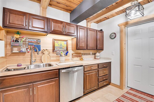 kitchen with beamed ceiling, sink, decorative light fixtures, stainless steel dishwasher, and light tile patterned flooring