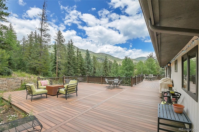 1774 Upper Bear Creek Rd, Evergreen, CO 80439 - wooden deck featuring outdoor dining space, a mountain view, outdoor lounge area, a forest view, and grilling area