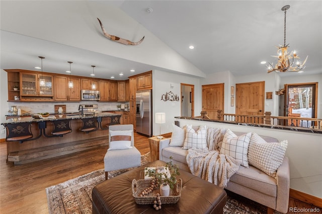 living area featuring an inviting chandelier, high vaulted ceiling, wood finished floors, and recessed lighting