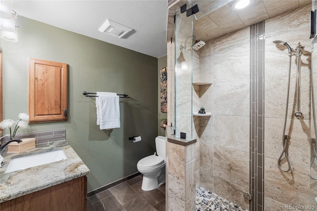 bathroom featuring toilet, a stall shower, vanity, and baseboards