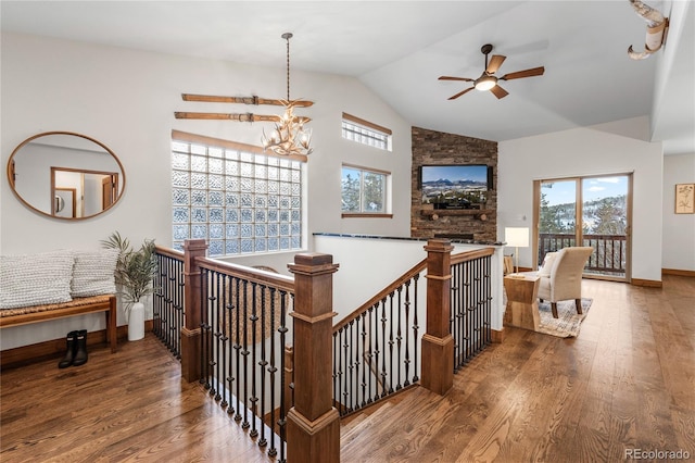 corridor featuring lofted ceiling, baseboards, wood finished floors, and an inviting chandelier