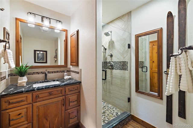 bathroom featuring a stall shower, backsplash, and vanity