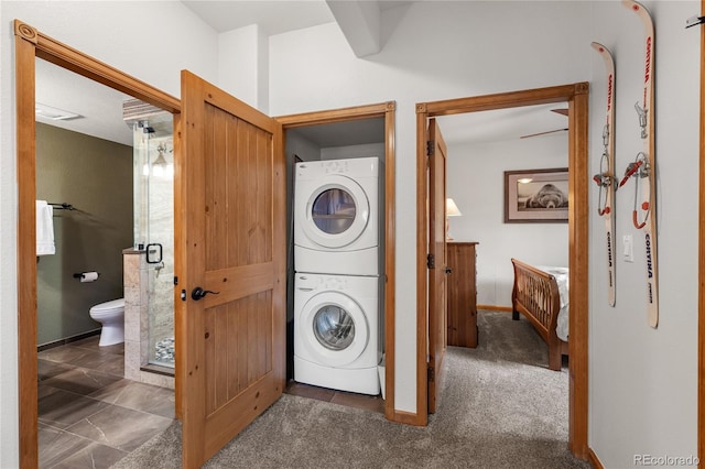 clothes washing area with carpet, laundry area, stacked washing maching and dryer, and baseboards