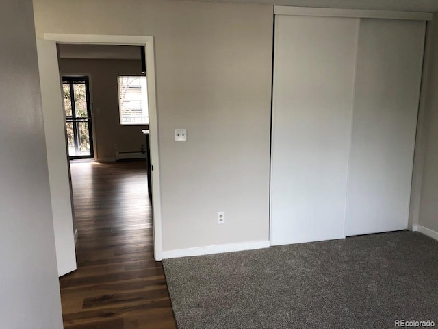 5875 E Iliff Ave Unit 203, Denver, CO 80222 - unfurnished bedroom featuring a baseboard radiator, baseboards, dark wood-style flooring, and a closet