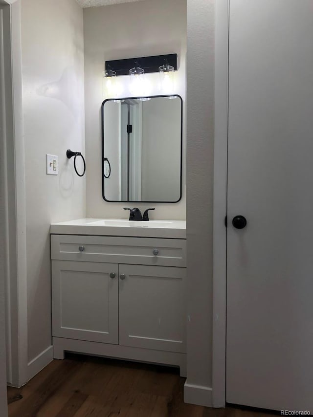 5875 E Iliff Ave Unit 203, Denver, CO 80222 - bathroom featuring wood finished floors, vanity, and baseboards