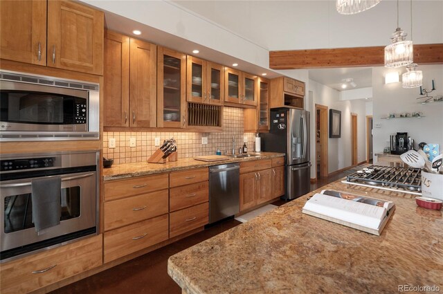 73244 US Highway 40, Tabernash, CO 80478 - kitchen featuring stainless steel appliances, brown cabinets, light stone counters, backsplash, and glass insert cabinets