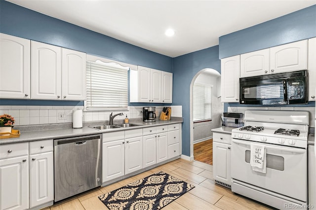 706 S Lincoln St, Denver, CO 80209 - kitchen with dishwasher, white gas range oven, black microwave, arched walkways, and white cabinetry